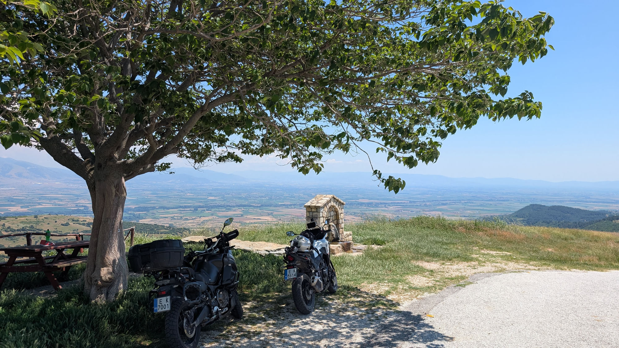 two bikes, a tree, a stone fountain, and a valley that goes on forever